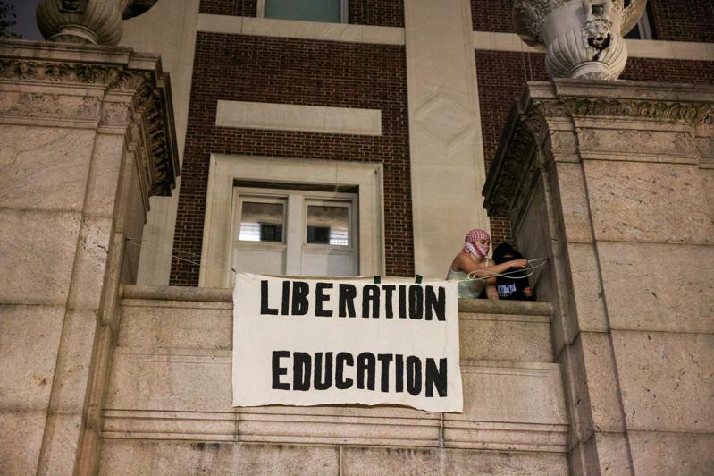 示威者在建筑上挂上「解放教育」的标语。（路透）