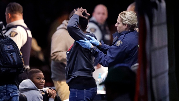 An RCMP officer frisks a woman as she is processed before being are turned over to the Canada Border Services Agency at a tent in Saint-Bernard-de-Lacolle, Que.