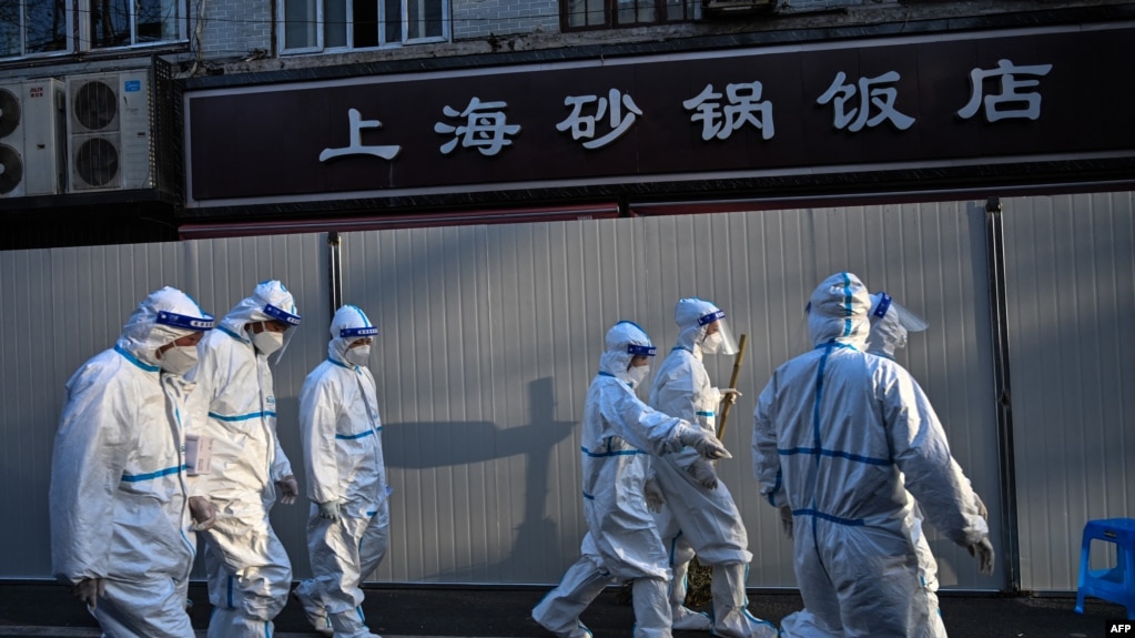 身穿防护服的防疫人员在上海一处因发现新冠疫情而被封闭的小区的屏障外。(2022年3月15日)