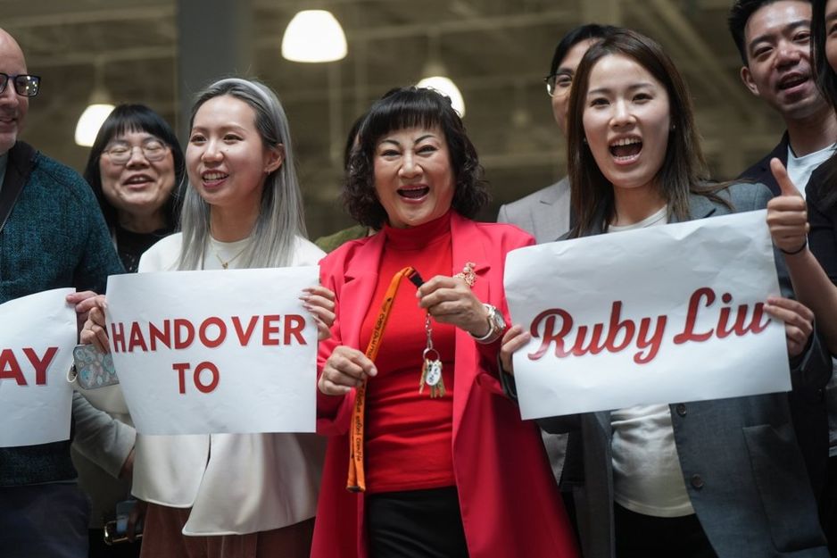 亿万富翁Ruby Liu(中)与她的员工在2025年6月26日于卑诗省Tsawwassen的Tsawwassen Mills购物中心举行的交接仪式上,手持一套曾由Hudson's Bay拥有的Saks Off 5th百货商店的钥匙。 THE CANADIAN PRESS/Darryl Dyck