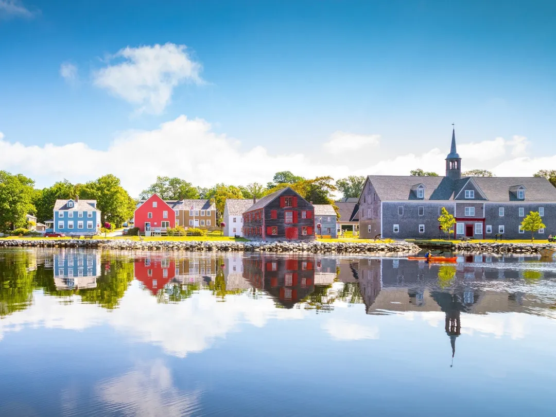 A view across the water of historic buildings as a kayaker paddles by